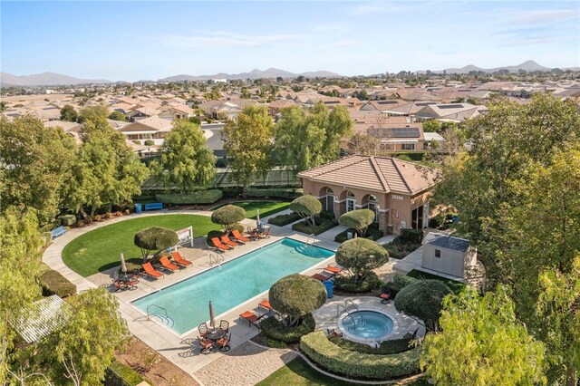 view of swimming pool with a community hot tub, a mountain view, a patio, and a lawn