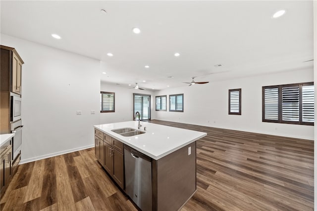 kitchen with stainless steel appliances, an island with sink, sink, and dark hardwood / wood-style flooring