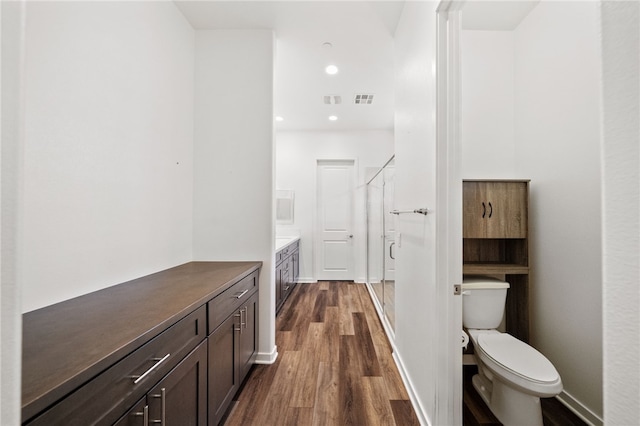 bathroom with vanity, hardwood / wood-style flooring, toilet, and walk in shower