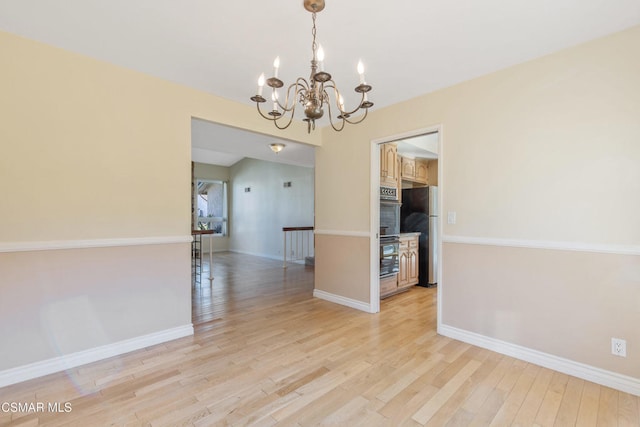 unfurnished dining area with a notable chandelier and light hardwood / wood-style floors