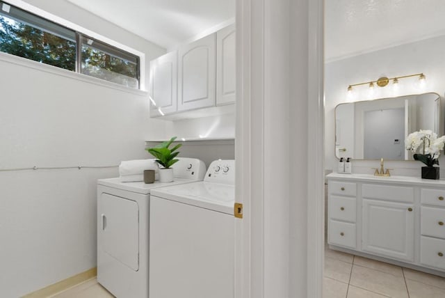 laundry area with sink, washer and clothes dryer, cabinets, and light tile patterned flooring