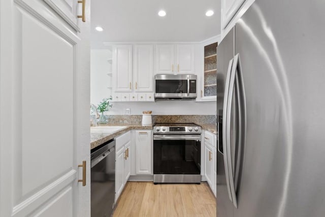 kitchen featuring sink, white cabinets, light stone counters, stainless steel appliances, and light hardwood / wood-style flooring