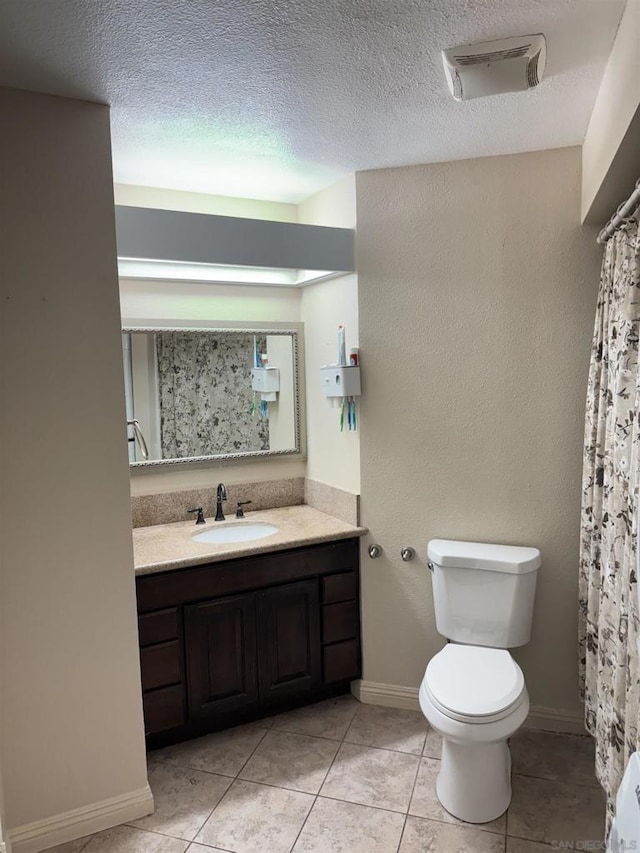 bathroom featuring tile patterned floors, vanity, toilet, and a textured ceiling