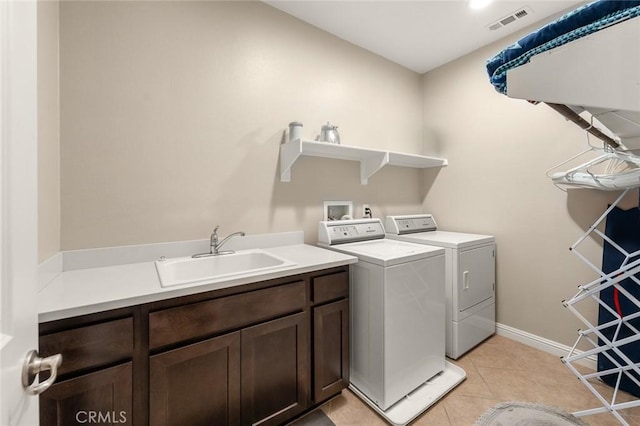 laundry room featuring sink, washer and clothes dryer, cabinets, and light tile patterned flooring