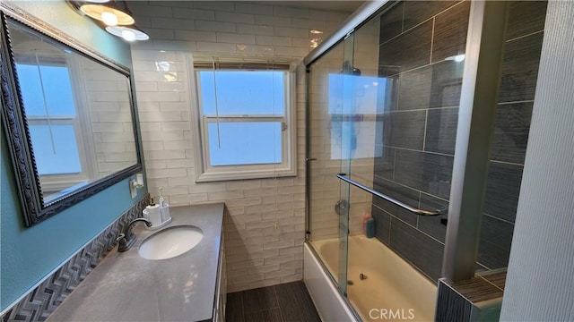 bathroom with tile walls, vanity, hardwood / wood-style flooring, and shower / bath combination with glass door