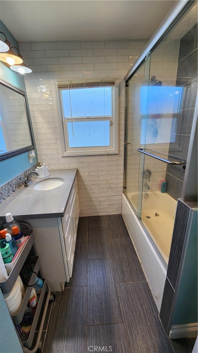 bathroom with vanity, shower / bath combination with glass door, and tile walls