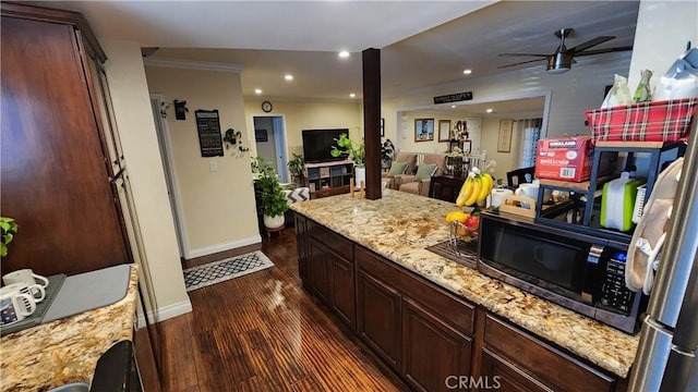 kitchen with dark hardwood / wood-style floors, ornamental molding, ceiling fan, light stone countertops, and dark brown cabinets