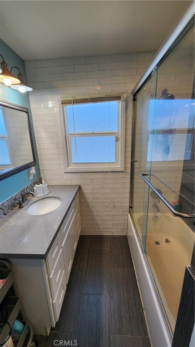 bathroom with bath / shower combo with glass door, wood-type flooring, and vanity