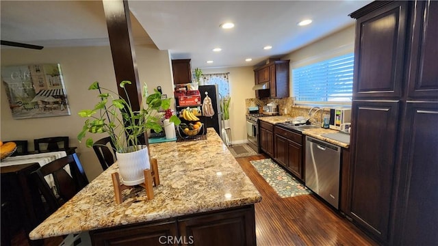 kitchen featuring appliances with stainless steel finishes, dark hardwood / wood-style floors, a center island, and a breakfast bar area