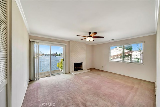 unfurnished living room featuring a water view, a fireplace, crown molding, and a wealth of natural light