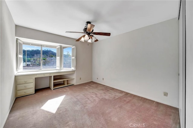 unfurnished bedroom featuring light colored carpet and built in desk