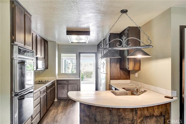 kitchen featuring appliances with stainless steel finishes, dark hardwood / wood-style floors, sink, kitchen peninsula, and a textured ceiling