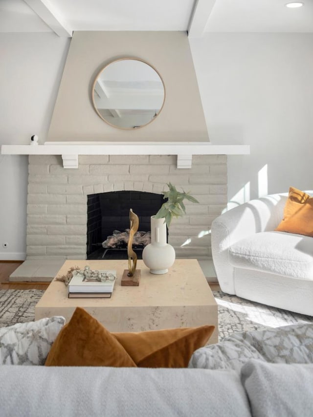 living room featuring hardwood / wood-style flooring, a brick fireplace, and beam ceiling