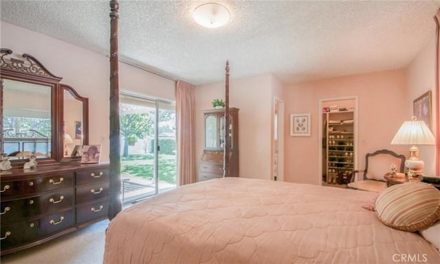 bedroom with light carpet, a spacious closet, access to outside, and a textured ceiling