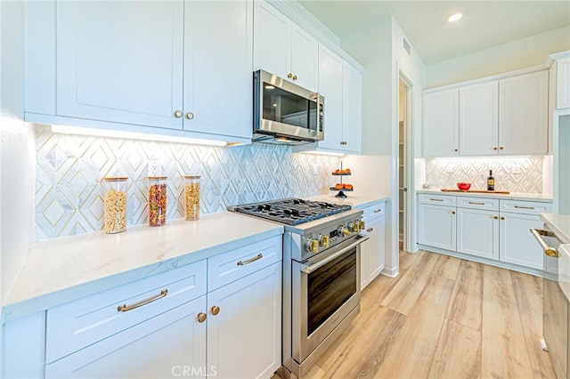 kitchen featuring white cabinetry, decorative backsplash, stainless steel appliances, and light wood-type flooring