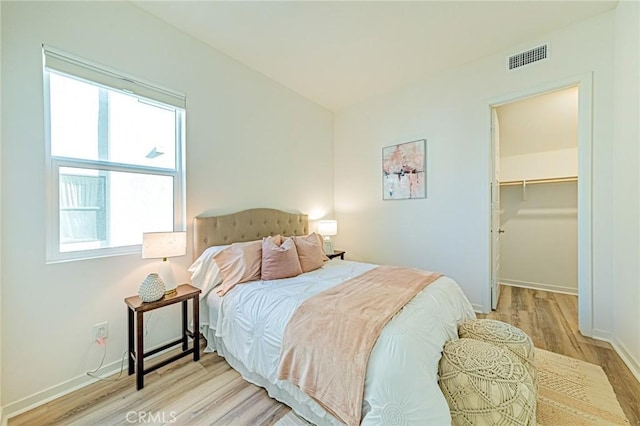 bedroom featuring a spacious closet and light wood-type flooring