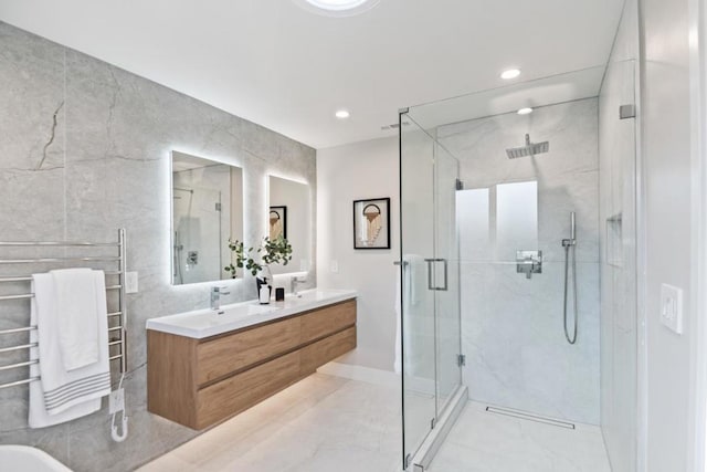 bathroom with vanity, tile walls, and a shower with shower door