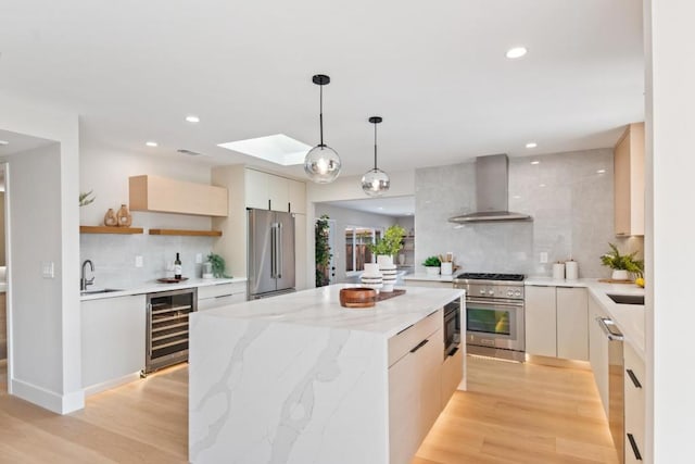 kitchen featuring wall chimney exhaust hood, high end appliances, hanging light fixtures, a kitchen island, and beverage cooler