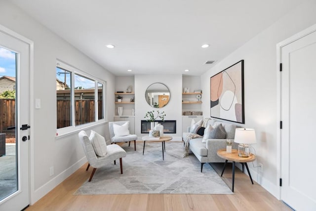 living room featuring built in features and light hardwood / wood-style flooring