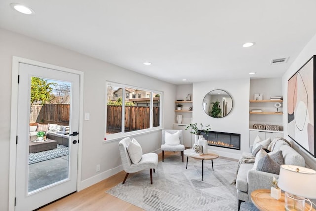 living room with built in features and light wood-type flooring