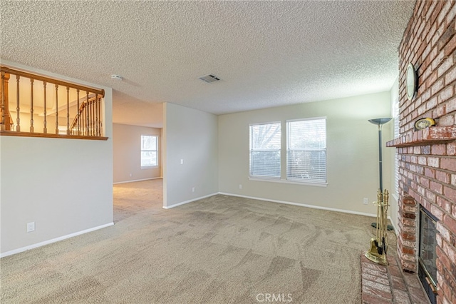 unfurnished living room with carpet floors, visible vents, a brick fireplace, a textured ceiling, and baseboards