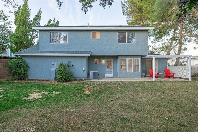 rear view of house with a yard, a patio area, fence, and stucco siding