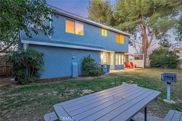 back of property featuring a yard, a fenced backyard, and stucco siding