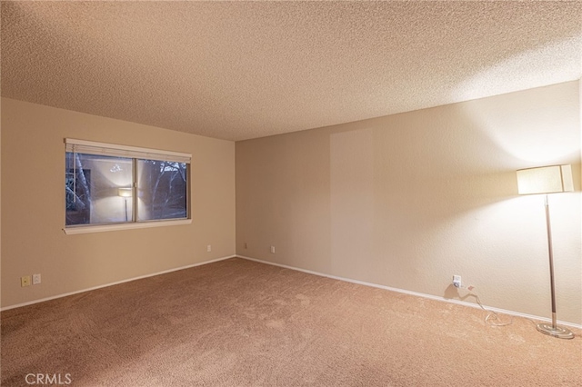 spare room with carpet floors, baseboards, and a textured ceiling