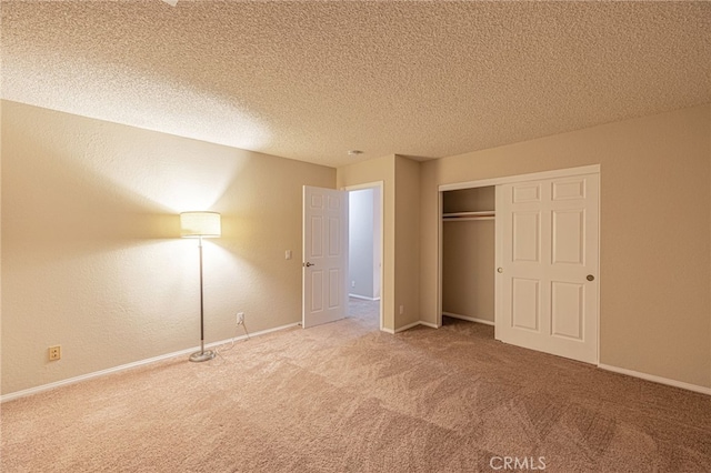 unfurnished bedroom with carpet, a textured ceiling, baseboards, and a closet