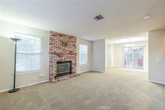 unfurnished living room featuring visible vents, baseboards, an inviting chandelier, carpet, and a brick fireplace