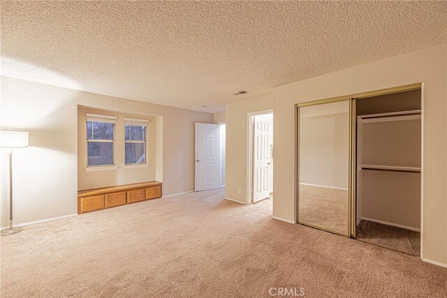 unfurnished bedroom with carpet floors, a closet, visible vents, and a textured ceiling