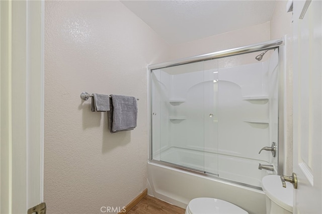 full bath featuring combined bath / shower with glass door, wood finished floors, toilet, and baseboards