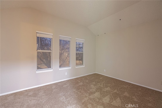 carpeted spare room with lofted ceiling, a textured ceiling, and baseboards