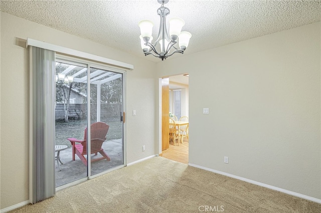 unfurnished dining area with light carpet, a textured ceiling, a chandelier, and baseboards