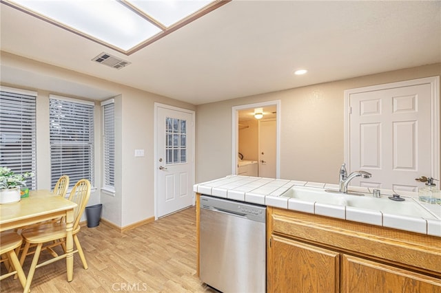 kitchen with tile countertops, visible vents, a sink, washer and dryer, and dishwasher