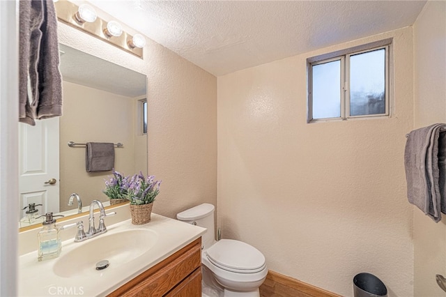 bathroom featuring a textured wall, vanity, toilet, and a textured ceiling