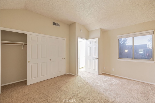 unfurnished bedroom with lofted ceiling, a closet, carpet flooring, and visible vents