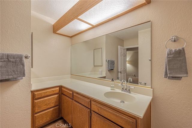 bathroom with a textured wall and vanity