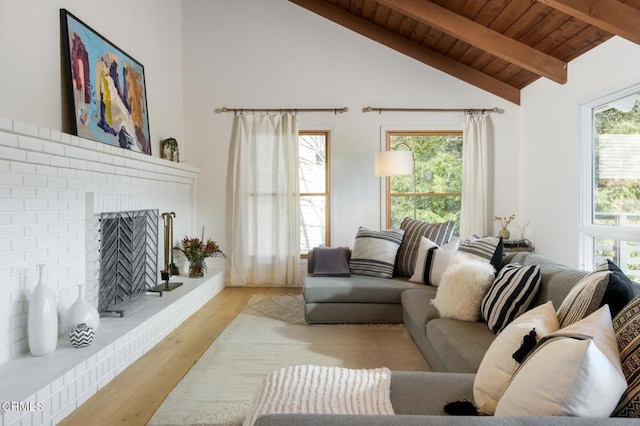 living room featuring a fireplace, light wood-type flooring, wood ceiling, a healthy amount of sunlight, and beam ceiling