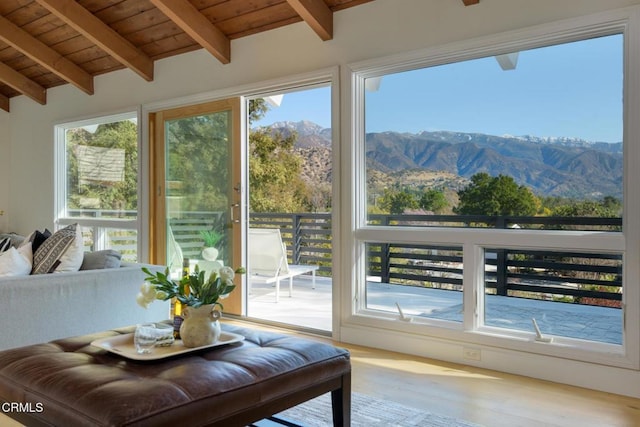 sunroom with a mountain view, a healthy amount of sunlight, vaulted ceiling with beams, and wood ceiling