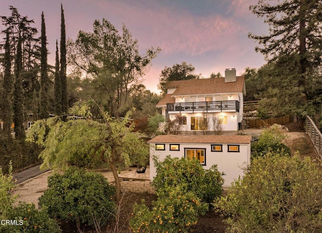 back house at dusk with a balcony