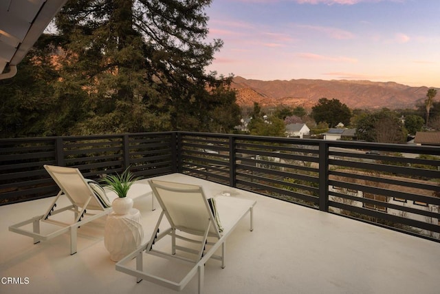 balcony at dusk featuring a mountain view