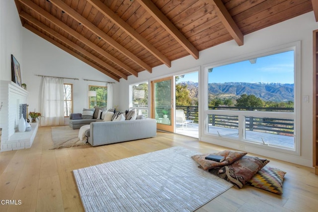 living room featuring high vaulted ceiling, beamed ceiling, wood ceiling, a mountain view, and a brick fireplace