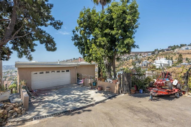 view of front of property with a garage, concrete driveway, fence, and stucco siding