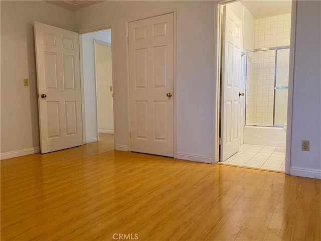 unfurnished bedroom featuring ensuite bathroom and light hardwood / wood-style flooring