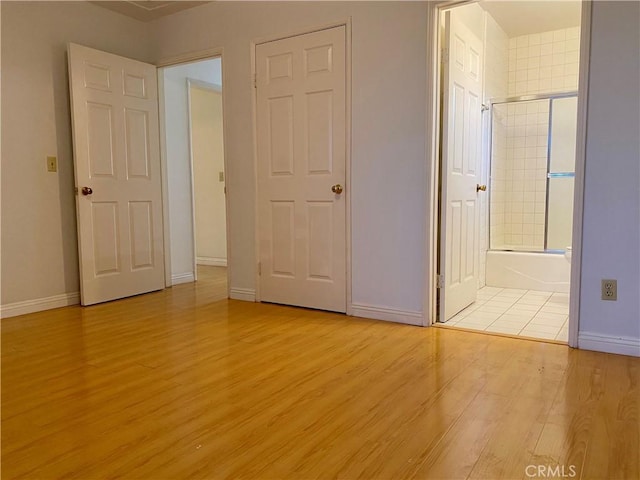 unfurnished bedroom with baseboards, ensuite bathroom, and light wood finished floors