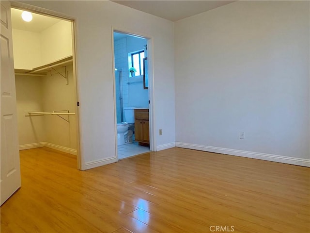 unfurnished bedroom featuring a spacious closet, light hardwood / wood-style floors, and a closet