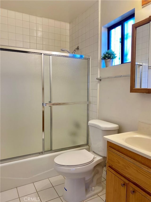 full bathroom with combined bath / shower with glass door, tile patterned flooring, vanity, and toilet