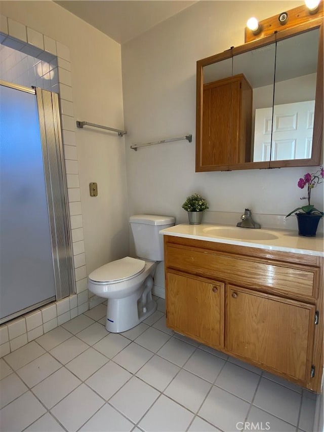 bathroom featuring tile patterned floors, toilet, a shower with shower door, and vanity