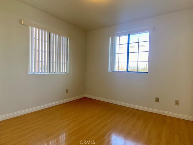 unfurnished room with baseboards and light wood-style floors